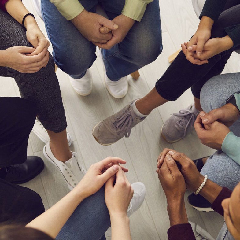 Top view of diverse people sitting in a close circle and talking to a grief therapist.