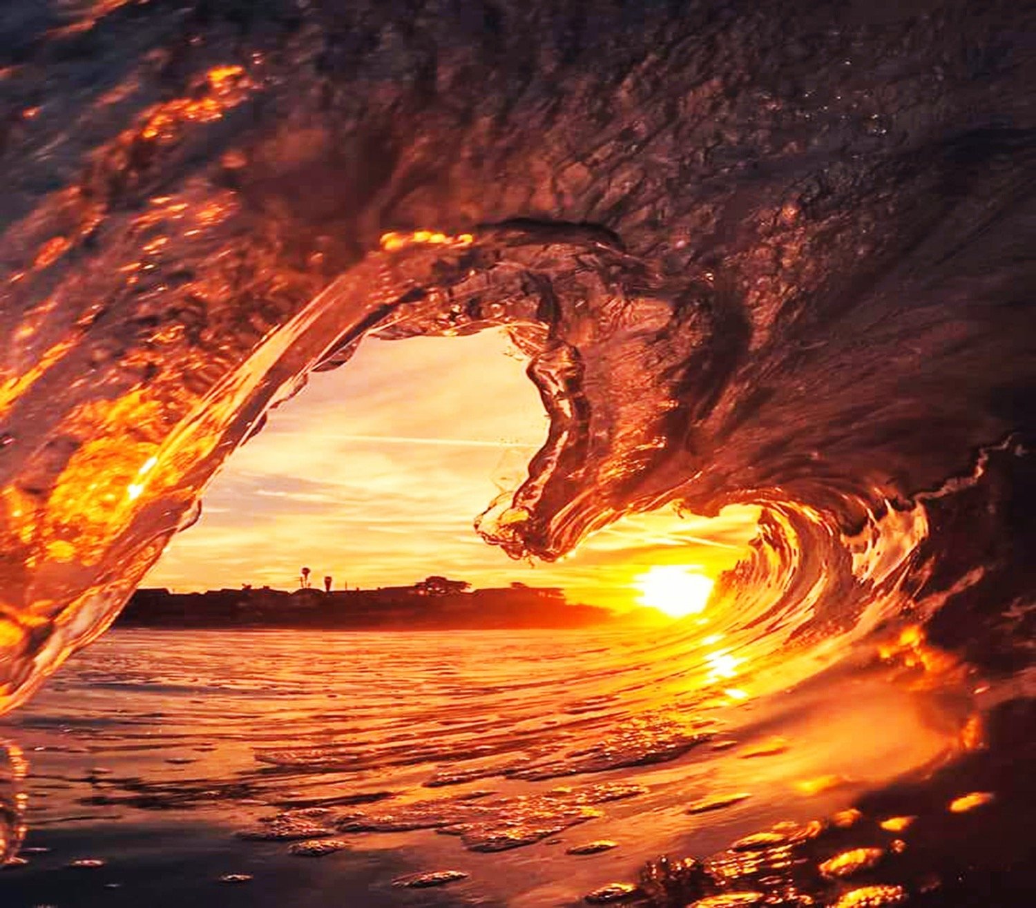 wave crashing into the ocean at sunset that is shaped like a heart